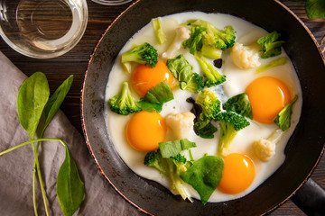 4 fried eggs with broccoli and spinach and spices in a pan on a dark  background, Breakfast