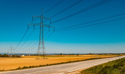 Beautiful view with a yellow rapeseed field and power lines near Wisselsing, Bavaria, Germany