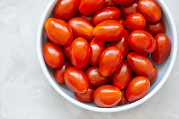 Fresh red cherry tomatoes in a bowl on light background. Selective focus, copy space