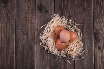 Fresh chicken eggs in a nest of hay on a wooden background. Copy space. Space for text
