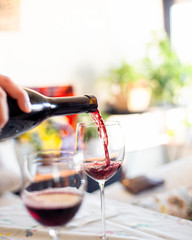 Man hand filling wine glass with red wine.