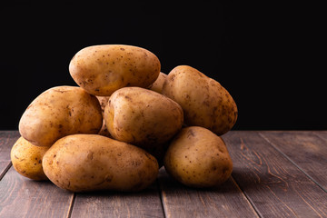 A pile of raw potatoes on a wooden background. Copy space. Space for text