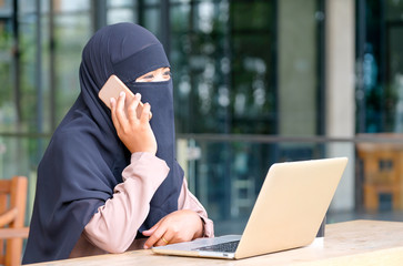 Muslim girl with hijab call to her co-worker or friends in front of laptop during work from home and stay at balcony in her house.