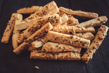 Salty crackers and seeds on black background