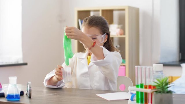 science, childhood and chemistry concept - girl in goggles playing with slime at home laboratory