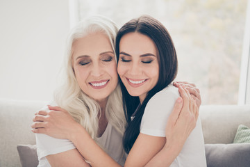 Close-up portrait of two nice attractive lovely cheerful dreamy women mom daughter granny granddaughter hugging enjoying holiday daydream in house apartment indoors