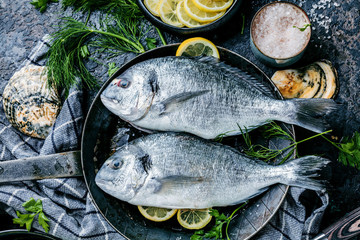 Fresh Dorodo or sea bream in black pan on dark background.
