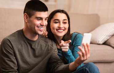 Fototapeta premium Couple using cell phone sitting on floor
