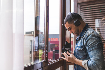 Young Latino Man Taking Pictures From Window at Home During Confinement.