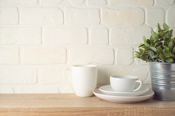 Kitchen background with dishware, cup, plate and plant on wooden shelf