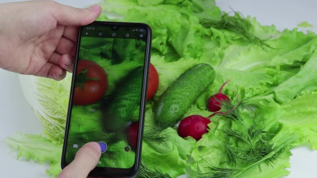 girl's hands take photos of fresh vegetables on her smartphone. food photography.
