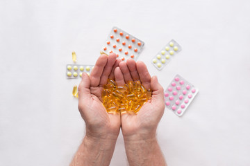 Senior hands with pills and medicine on the table. Wrinkled hand of an old woman holding colorful pills. Old age. Health care for the elderly.