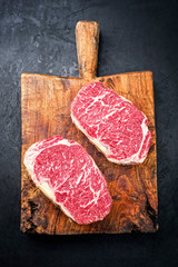 Raw dry aged wagyu entrecote beef steak roast as top view on a rustic wooden cutting board