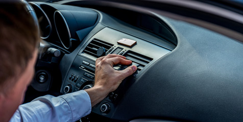 Transportation vehicle and car auto audio concept - man using car audio and radio stereo on car panel