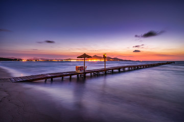 Fototapeta na wymiar A wooden pier at Playa de Muro beach in Mallorca