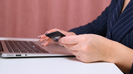 female hands make a purchase on the Internet using a laptop, payment by card, close-up.