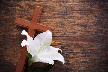 Wooden cross and white lily on rustic table