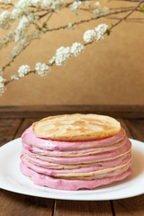 selbstgemachtem geschichtete Pfannkuchentorte mit Creme aus Sahne, Quark und Himbeere auf braunem Tisch aus Holz 