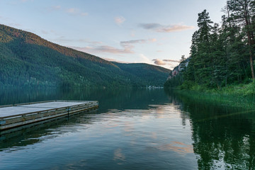 Wooden dock facing a calm lake during a summer evening british columbia canada.