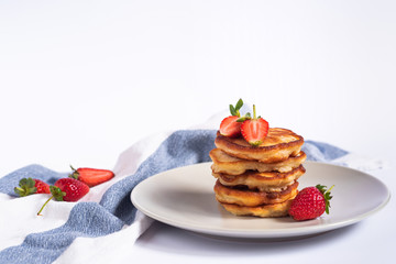 Russian pancakes oladi with strawberries on a grey plate with textiles on the background 