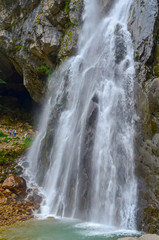 Gega waterfall in the mountains of Abkhazia. A group of tourists next to that. It is located in the northern spurs of the Gagra Range at an altitude of 530 meters above sea level.