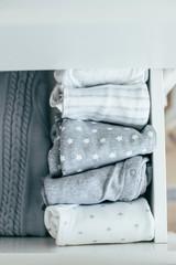 Top view of baby or newborn things of white, blue and grey colors are in the drawer. Lady fly system, kondo, konmary concept. Home lifestyle.
