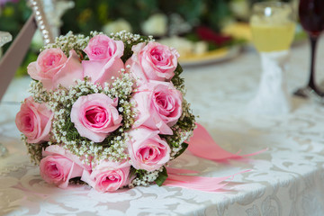 pink ribbon .pink engagement flowers on white table . Bride and groom with Engagement gold rings put on the pink wedding bouquet . Pink engagement bouquet .