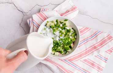 Step by step preparation of cold okroshka soup with sausage, step 7- pouring kefir to the bowl top view