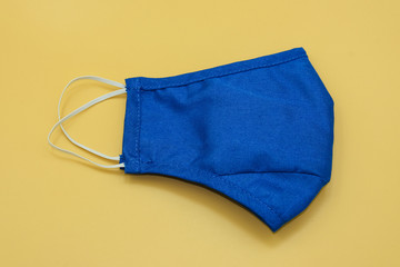 blue fabric mask surgical filter dust pollution and disease corona virus or covid -19 . safety medical equipment. Isolated on yellow background.
