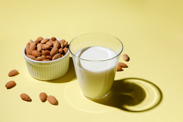 Almond milk in a glass on yellow background - alternative dairy