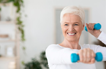 Portrait Of Happy Elderly Woman Exercising With Dumbbells At Home