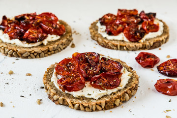 Round slices of wholemeal bread with grilled tomatoes on cream cheese