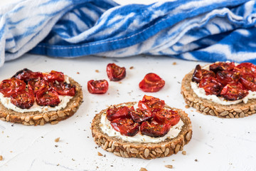 Round slices of wholemeal bread with grilled tomatoes on cream cheese