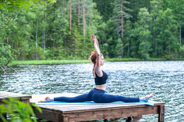 Fototapeta na wymiar Young yogi girl practicing yoga, stretching in Monkey God exercise, Splits, Hanumanasana pose on the lake. The concept of appeasement, healthy lifestyle.