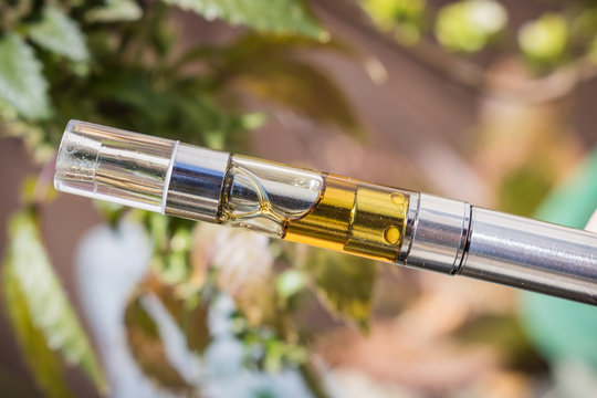 A Vape Pen With Golden Cannabis Extracted Oil Filled Cartridge. Isolated Up-close