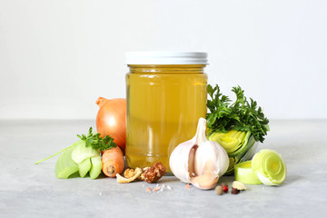 Vegetable broth ready in a glass jar with vegetables and spices