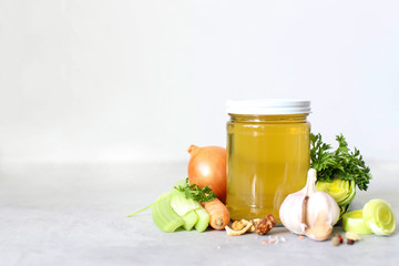 Vegetable broth ready in a glass jar with vegetables and spices