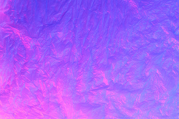 Fototapeta na wymiar Background from purple recyclable polyethylene in neon pink light. Eco, zero waste, alternative to plastic concept. Flat lay. Horizontal. Closeup