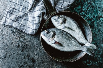 Fresh Dorodo or sea bream in black pan on dark background.