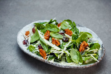 Apple and celery salad with spinach leaves on a white plate close up side view