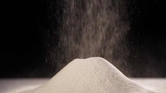 pile of flour on the table. sifting flour on a dark background