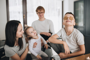 The family prepares gingerbread cookies in the kitchen. Dad, mom, son, daughter, brother and sister. Knead dough, cookie cutters, New Year, Christmas, holiday dinner. Gray homewear.