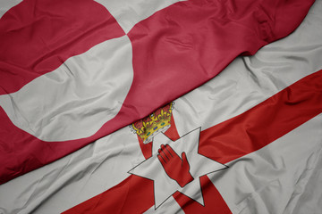 waving colorful flag of northern ireland and national flag of greenland.