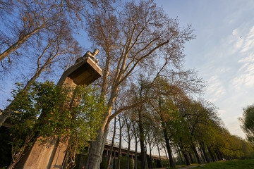 Statue aus Stein kniet auf hohem Podest und h&auml;lt kaum sichtbaren Tonkrug, steil nach oben ab gelichtet mit Weit Winkel, Im Rosenstein Park Stuttgart, Deutschland 