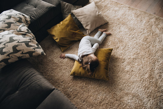 Family in a big house. Lifestyle Home comfort. Children at home. The girl is playing on the floor. The child fell asleep on a pillow on the floor. Textile.