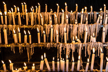hundreds of candles at a wake, lit by religious looking for graces and promises - 343584005
