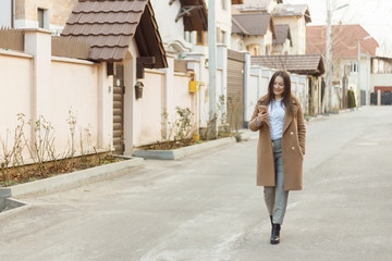 Obraz premium Portrait of young beautiful girl outside. Positive young woman spending time outside with her mobile device. Girl with mobile phone.