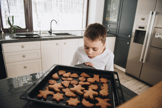 Family in a big house. Lifestyle Home comfort. Children at home. Bake gingerbread cookies with mom. Ready hot cookies. Beautiful kitchen.