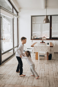 Family in a big house. Lifestyle Home comfort. Children at home. Beautiful kitchen. Brother and sister play in the kitchen. Windows to the floor. Huge windows.