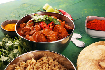 Chicken tikka masala spicy curry meat food in pot with rice and naan bread. indian food on table